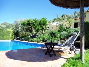 Una mesa y una silla junto a una piscina. en Rural House in Antequera, en La Joya
