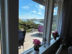 a window with flowers and a view of the ocean at 4 star holiday home in Espevær in Espevær