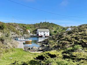 een boot is aangemeerd in het water naast een huis bij 6 person holiday home in Espevær-By Traum in Espevær