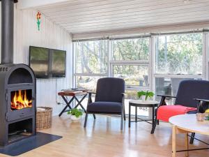 un soggiorno con camino, tavolo e sedie di Bright Coastal Retreat in Vorupor-By Traum a Thisted