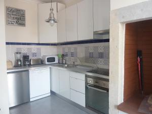 a kitchen with white cabinets and a stove top oven at Casa do Beco in Lisbon