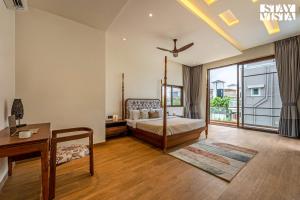 a bedroom with a bed and a desk and a window at StayVista at Villa Alora with Jacuzzi in Lonavala