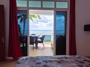 a bedroom with a view of the ocean from a balcony at Baywatch Apartment in La Gaulette