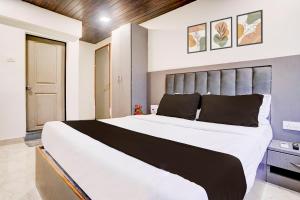 a bedroom with a large white bed with a gray headboard at Hotel Relax Residency in Mumbai