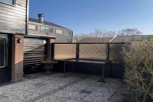a bench sitting on a patio next to a building at Holiday Home Warmenhuizen near Dunes in Warmenhuizen