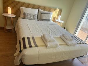 a large white bed with two pillows on it at Porto Santo Rentals in Porto Santo