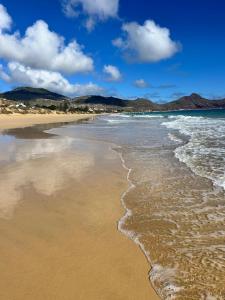 a beach with the ocean and mountains in the background at Porto Santo Rentals in Porto Santo