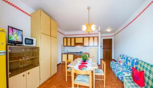 a kitchen and a living room with a table and a couch at Residence Sabrina in Bibione