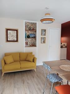 a living room with a yellow couch and a table at Petite maison cosy à Moret-sur-Loing, cour privée in Moret-sur-Loing