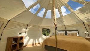 a bedroom in a tent with a bed and an umbrella at Agger Glamping - Havtornen in Vestervig