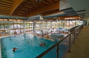 a large indoor swimming pool with people in it at Lakókocsi termál fürdő kemping in Túrkeve