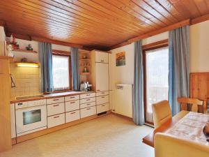 a kitchen with white cabinets and a wooden ceiling at Apartment in Niedernsill near Ski Slopes in Niedernsill