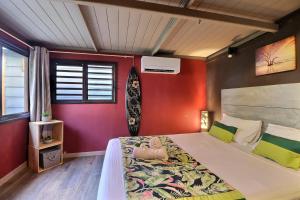 Un dormitorio con una cama grande con paredes rojas. en Fare Vainina - Charmante maison de plage près du golf, en Moorea