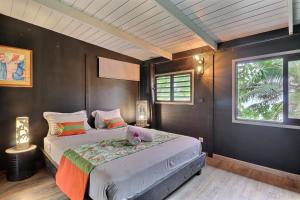 Un dormitorio con dos camas y dos ventanas. en Fare Vainina - Charmante maison de plage près du golf, en Moorea