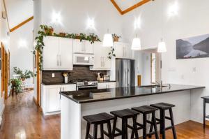 a kitchen with white cabinets and black counter tops at Spa and Lakeside - La Luz del Dia in Saint-Didace +36 photos