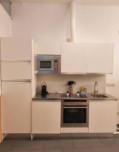 une cuisine avec des armoires blanches et un micro-ondes dans l'établissement Apartamento Loft Desing City Center, à Tolède