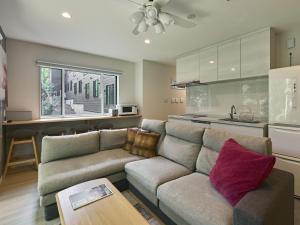 a living room with a couch and a kitchen at The Seasons Apartments Hakuba in Hakuba