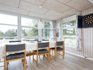 a dining room with a table and chairs and windows at 8 person holiday home in Struer in Struer