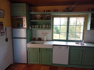 eine Küche mit grünen Schränken und einem weißen Kühlschrank in der Unterkunft Tranquil Garden Hideaway in Puy-lʼÉvêque