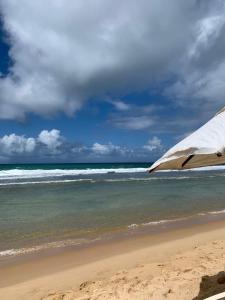 ein Strand mit einem Sonnenschirm und dem Meer in der Unterkunft Bangalô - Beach Class Resort - Praia Muro Alto - Porto de Galinhas - by HomeTemp in Porto De Galinhas + 34 Fotos