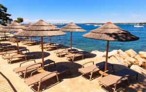 a group of chairs and umbrellas on a beach at Villa Gigi by Villas Guide in Poreč