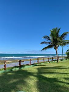 ein Zaun am Strand mit einer Palme in der Unterkunft Bangalô - Beach Class Resort - Praia Muro Alto - Porto de Galinhas - by HomeTemp in Porto De Galinhas
