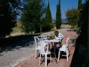 a table with white chairs and flowers on it at Tuscan Hilltop Farm Stay in Castelnuovo Berardenga