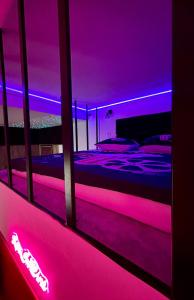 a bedroom with a bed with purple lights at LOVE IN CINÉ Appartement cinéma balnéo in Pamiers