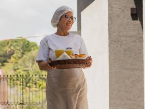 une femme tenant un panier d'oranges et de jus dans l'établissement Pousada Nori - Por MME Hospitalidade, à São Miguel dos Milagres