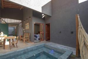 a swimming pool in a house with a table and a patio at Pousada Nori - Por MME Hospitalidade in São Miguel dos Milagres