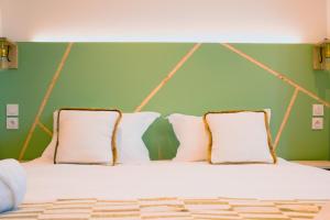 a bed with white pillows and a green wall at Sainte-Cécile in Marseille