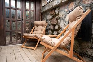 two rocking chairs sitting next to a stone wall at Škrka cotege - center of Zabljak in Žabljak