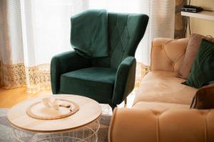 a living room with a green chair and a coffee table at Kucica u centru Zabljaka in Žabljak