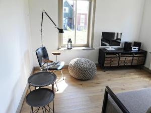 a living room with two chairs and a television at Holiday Home Zoutkamp near Lauwersmeer in Zoutkamp +23 photos