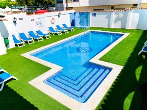 a swimming pool in the middle of a lawn with chairs at Hotel Comarruga Platja in Comarruga