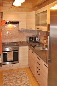 a kitchen with wooden cabinets and a stainless steel appliance at Chata Iľanovka in Belá