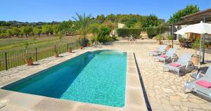 una piscina en un patio con sillas y sombrilla en Ferienhaus in Selva mit Gepflegtem Garten, en Selva