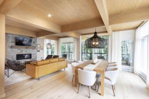 a living room with a dining table and a fireplace at Chalet Mid-Century - Lakeside Joseph - Le Charlo in Saint-Pierre-Baptiste