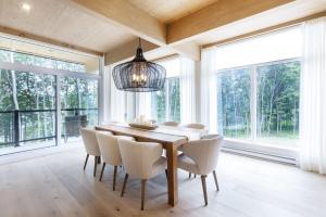 a dining room with a table and chairs and windows at Chalet Mid-Century - Lakeside Joseph - Le Charlo in Saint-Pierre-Baptiste