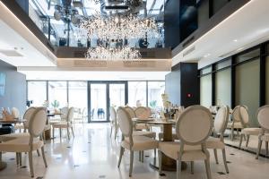 a dining room with tables and chairs and a chandelier at Le Blanc Cotroceni Hotel in Bucharest