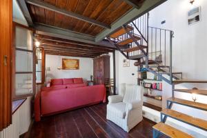 a living room with a red couch and a spiral staircase at Casale La Selva Cottege grande in Piano Porlezza
