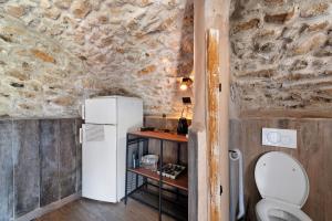 a small kitchen with a white refrigerator in a stone wall at Casale La Selva Cottege grande in Piano Porlezza +30 photos