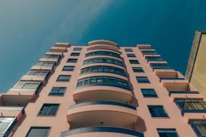 a tall pink building with a blue sky in the background at Wicalia ShortStays in Mem Martins