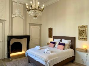 スミュール・アン・ノーソワにあるHôtel Particulier, Maison Jazey.のベッドルーム1室(ベッド1台、暖炉、シャンデリア付)