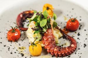 a plate of food with a sausage and tomatoes at Hotel dP Olbia - Sardinia in Olbia
