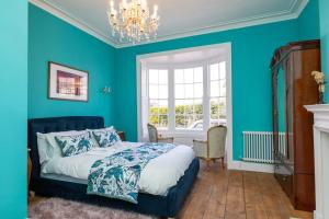 a blue bedroom with a bed and a chandelier at Luxury Georgian home & garden by the sea, 6 guests in Bognor Regis