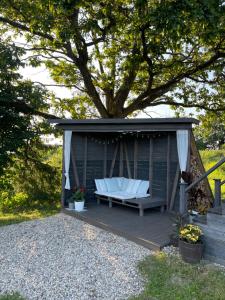a gazebo with a bench and a tree at Cottage Avene in Jūdaži