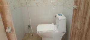a bathroom with a white toilet with a phone on it at Shivalaya Rooms in Tiruvannāmalai +5 photos