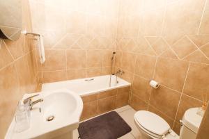een badkamer met een wastafel, een toilet en een bad bij Queens View 33 in Margate