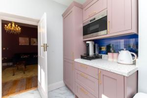 a kitchen with pink cabinets and a microwave at Luxury Georgian home & garden by the sea, 6 guests in Bognor Regis +18 photos